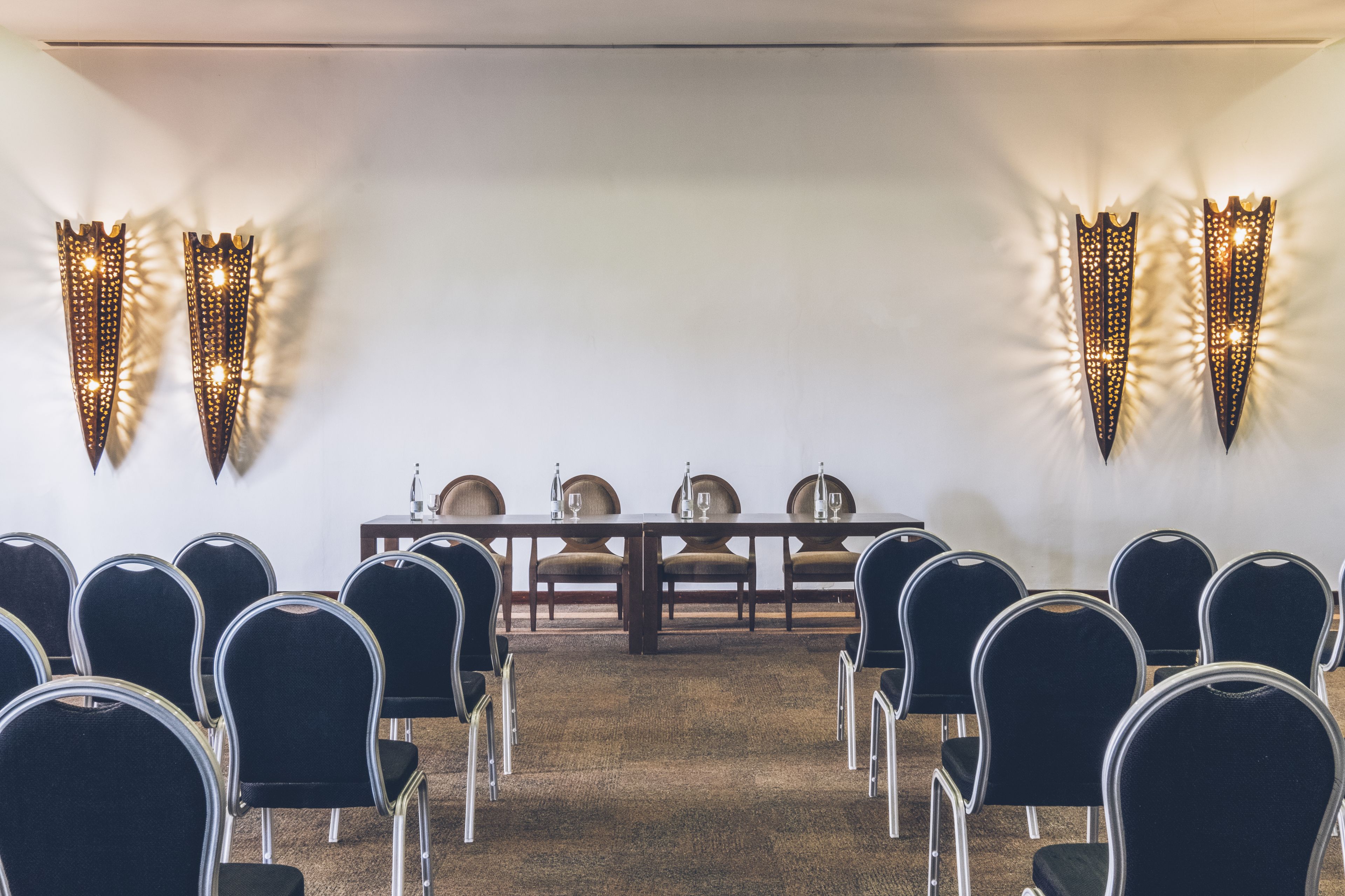 A conference room with a long table, chairs, and decorative wall sconces.