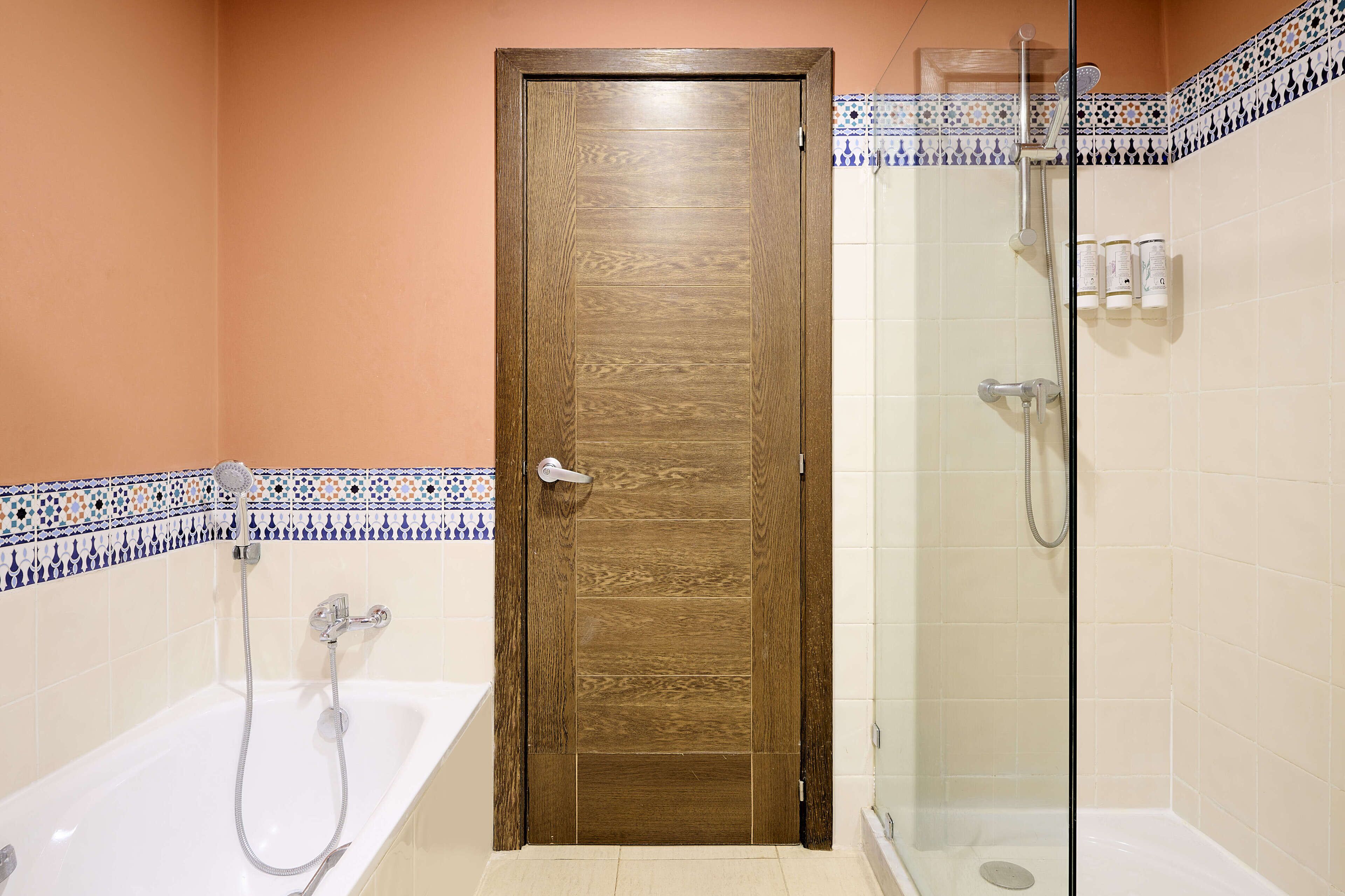 A bathroom with a wooden door, a glass shower enclosure, and a bathtub.