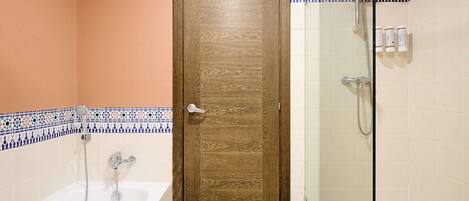 A bathroom with a wooden door, a glass shower enclosure, and a bathtub.