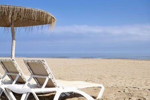 On the beach, white sand, sun loungers, beach umbrellas