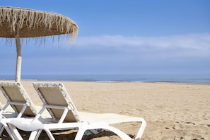 Am Strand, weißer Sandstrand, Liegestühle, Sonnenschirme