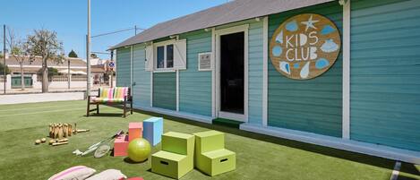 Een kinderclub met een speelruimte, inclusief sportattributen en kleurrijke kussens.