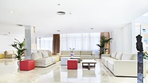 A modern living room with a beige sofa set, a red ottoman, and a coffee table. - Grupotel Port d'Alcudia (Alcúdia)