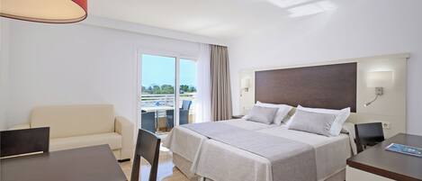 Une chambre d’hôtel équipée d’un lit, d’un bureau, d’une chaise, d’un canapé et d’un balcon avec vue.