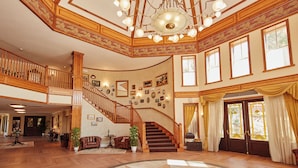 Un hall d’entrée spacieux, agrémenté d’un magnifique escalier, d’un parquet en bois et d’un lustre.