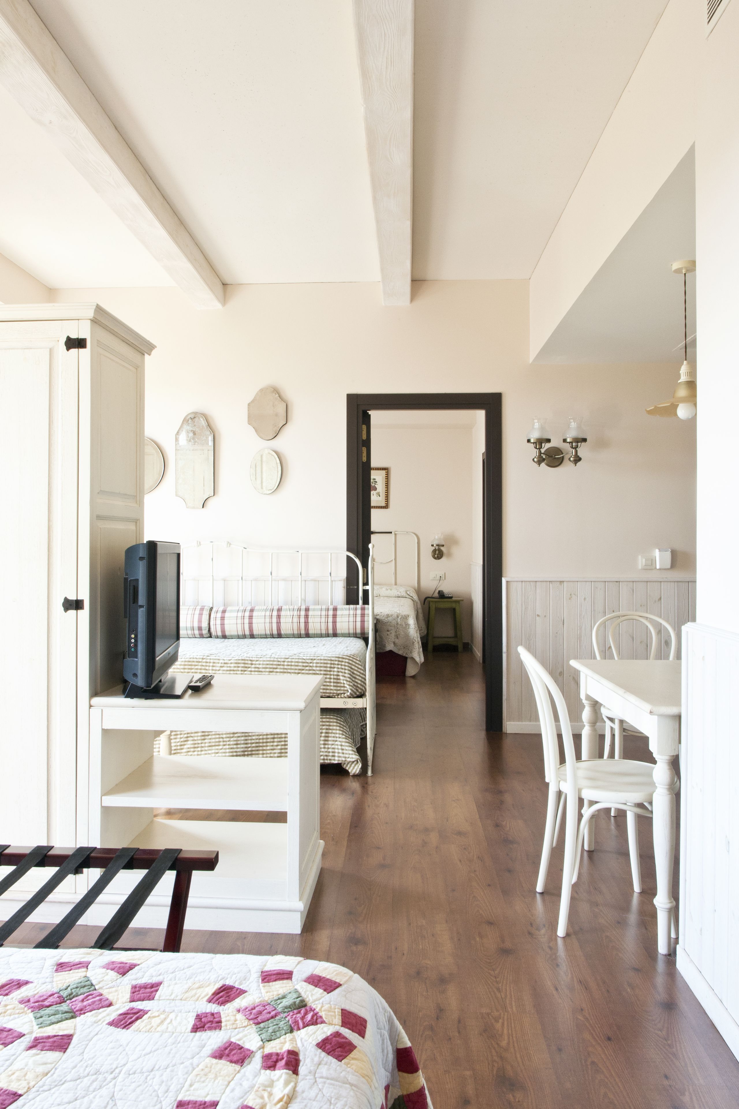 A bedroom with a bed, bedside table, and a desk with chairs.