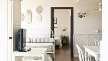 A bedroom with a bed, bedside table, and a desk with chairs.