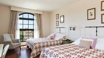 Una habitación con dos camas, una silla y un ventanal con cortinas.