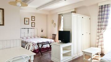 A bedroom with a bed, a TV, a wardrobe, a desk, and a chair.
