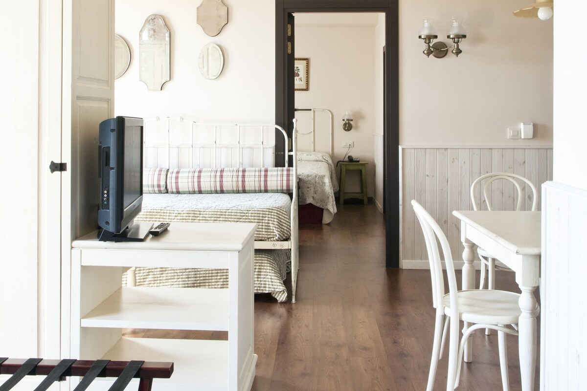 Une chambre à coucher avec un lit, une table de chevet et un bureau avec une chaise. Une porte donne acc ès à une autre pièce.