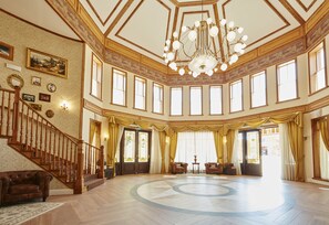 Stunning interior with a grand chandelier, circular patterned floor, and elegant artwork.