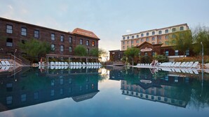 Un hôtel doté d’une piscine, de chaises longues et dont la façade se reflète dans l’eau.