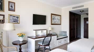 Una habitación de hotel con cama, escritorio con silla, televisor y cuadros en la pared.