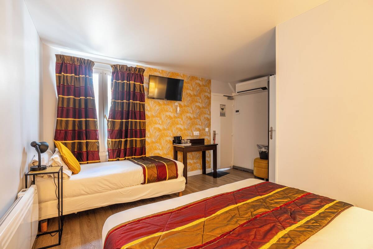 A hotel room with two beds, a TV, a desk, and a wardrobe.