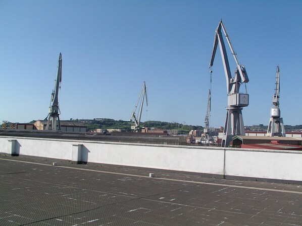 A rooftop with solar panels, a crane, and a bridge in the background. - Hotel Naval Sestao (Sestao)