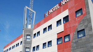 Un edificio de hotel con fachada roja y blanca, un letrero llamativo que dice "HOTEL NAVAL", y una estructura de grúa a la izquierda.
