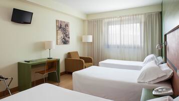 Een hotelkamer met twee bedden, een bureau, een stoel, een televisie en een telefoon.