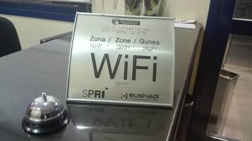 Un panneau indiquant la présence d’une connexion Wi-Fi dans une pièce équipée d’une table et d’une cloche.