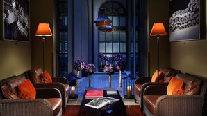 A lounge area with wicker sofas, a coffee table with magazines, and two floor lamps. - Hotel L'Orologio Firenze (Florence)