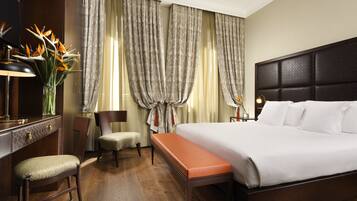 Una habitación de hotel con una cama grande, un escritorio con lámpara, una silla y un banco.