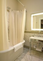 Un bagno con una vasca, un lavandino in vetro e uno specchio con illuminazione.