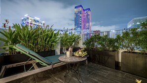Une terrasse sur le toit, avec une table, des chaises et des plantes en pot.