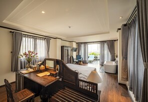 Habitación de hotel con cama, escritorio, silla, lámpara y baño con bañera y lavamanos.