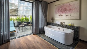 Une salle de bain moderne avec une baignoire sur pieds, un comptoir en marbre et une grande fenêtre agrémentée de rideaux.