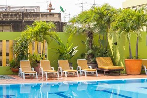 Un espace aménagé au bord de la piscine, avec des chaises longues et des plantes en pot.