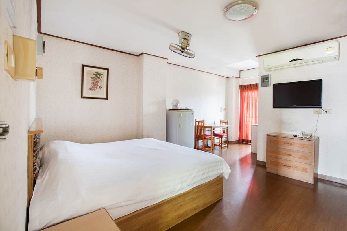 Habitación de hotel con cama, escritorio, silla, cómoda y televisor.