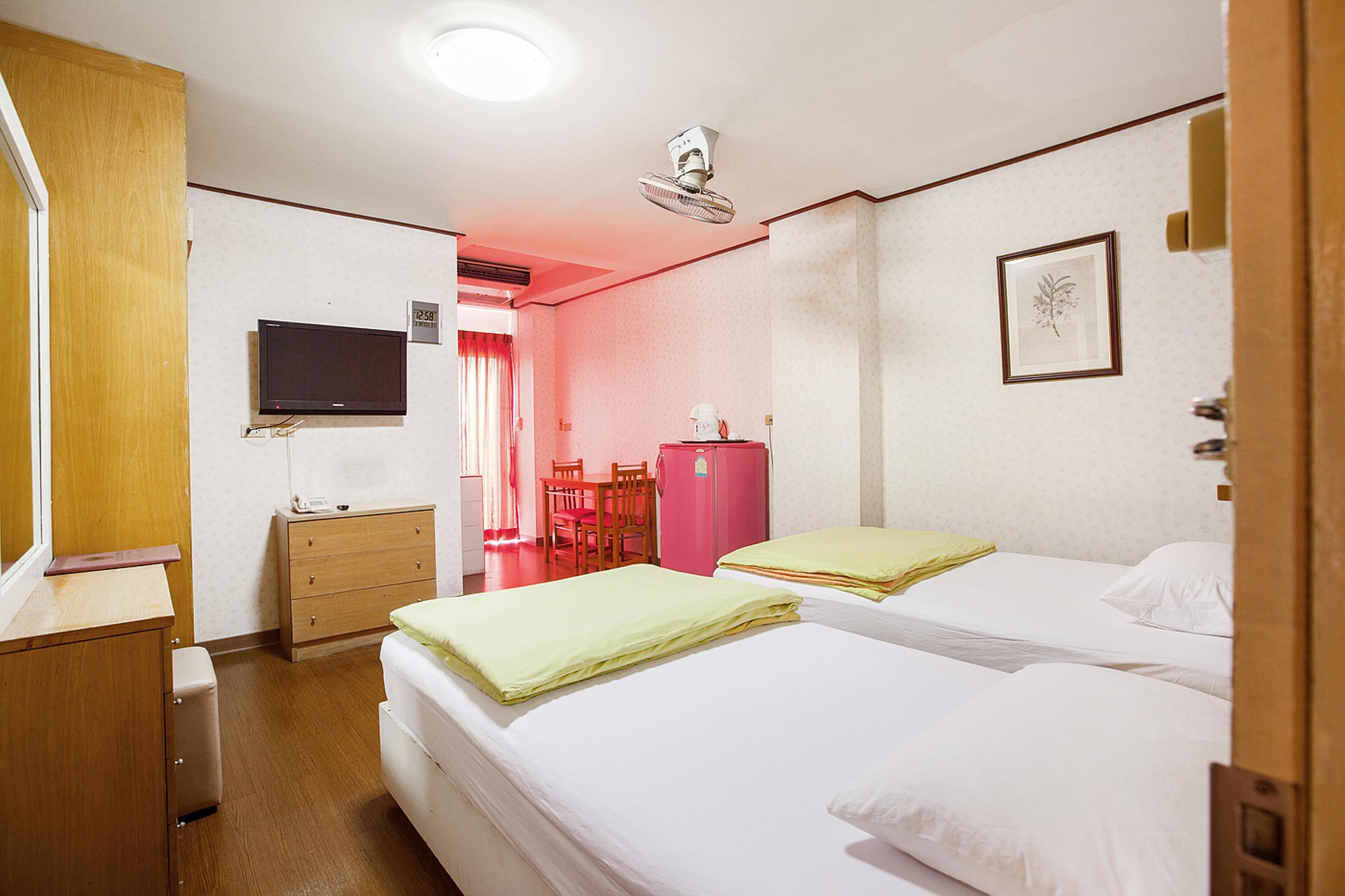 Una habitación de hotel con dos camas, televisión, escritorio y armario.