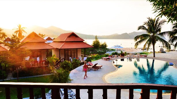 Un resort con piscina, playa y vistas a la montaña.