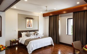 A hotel room with a large bed, a wooden floor, a ceiling fan, a window with curtains, and a wall-mounted artwork. - Keys Select by Lemon Tree Hotels, Malabar Gate, Kozhikode (Kozhikode)