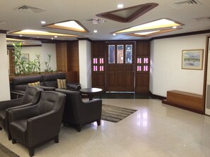 A lobby with a sofa, chairs, a small table, and a wooden door with stained glass windows.