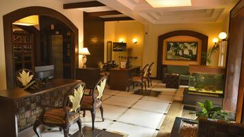 Experience the elegant lobby, featuring a reception desk, ornate chairs, a large fish tank, and framed artwork.