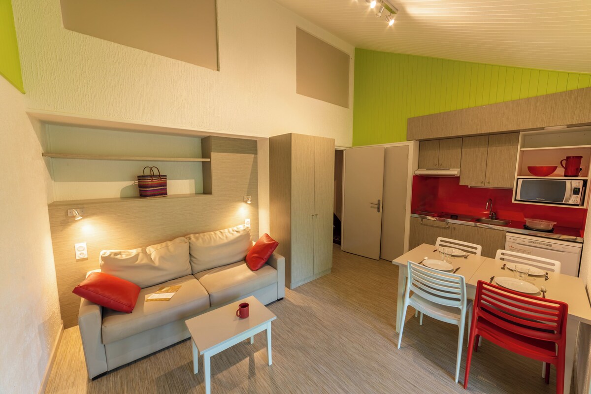 A modern living room with a sofa, coffee table, and a dining area with chairs and a table.