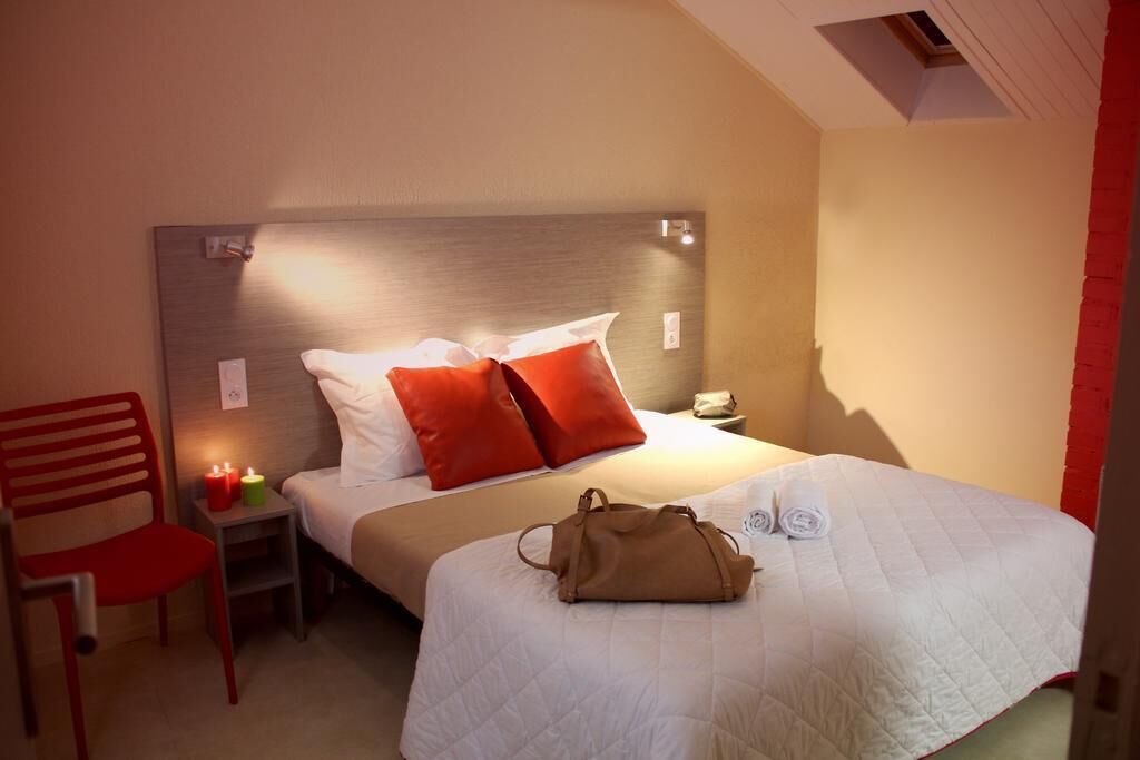 A hotel room with a bed, a chair, a nightstand, and a lamp.