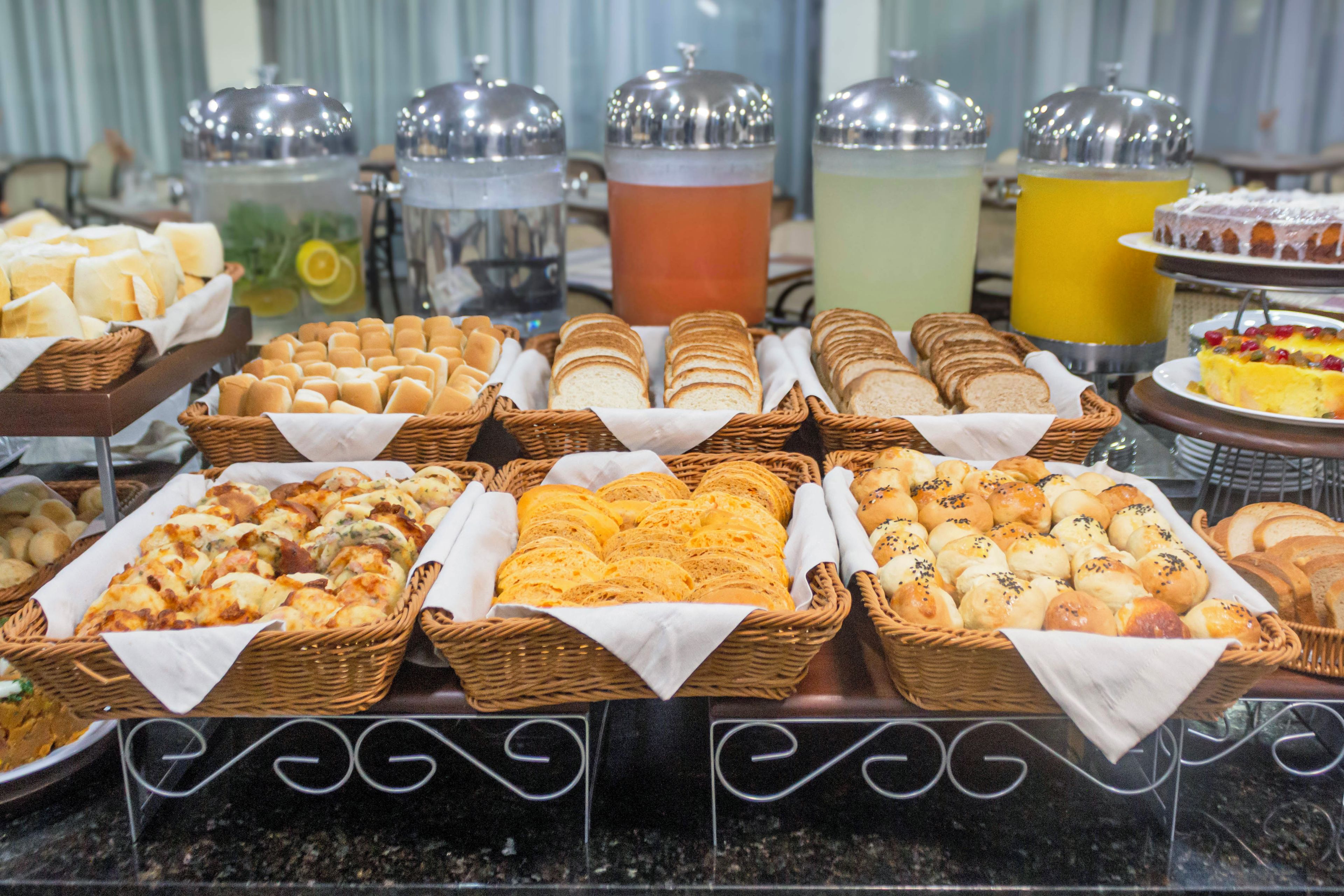 A buffet with various breads and pastries, and multiple beverage dispensers.