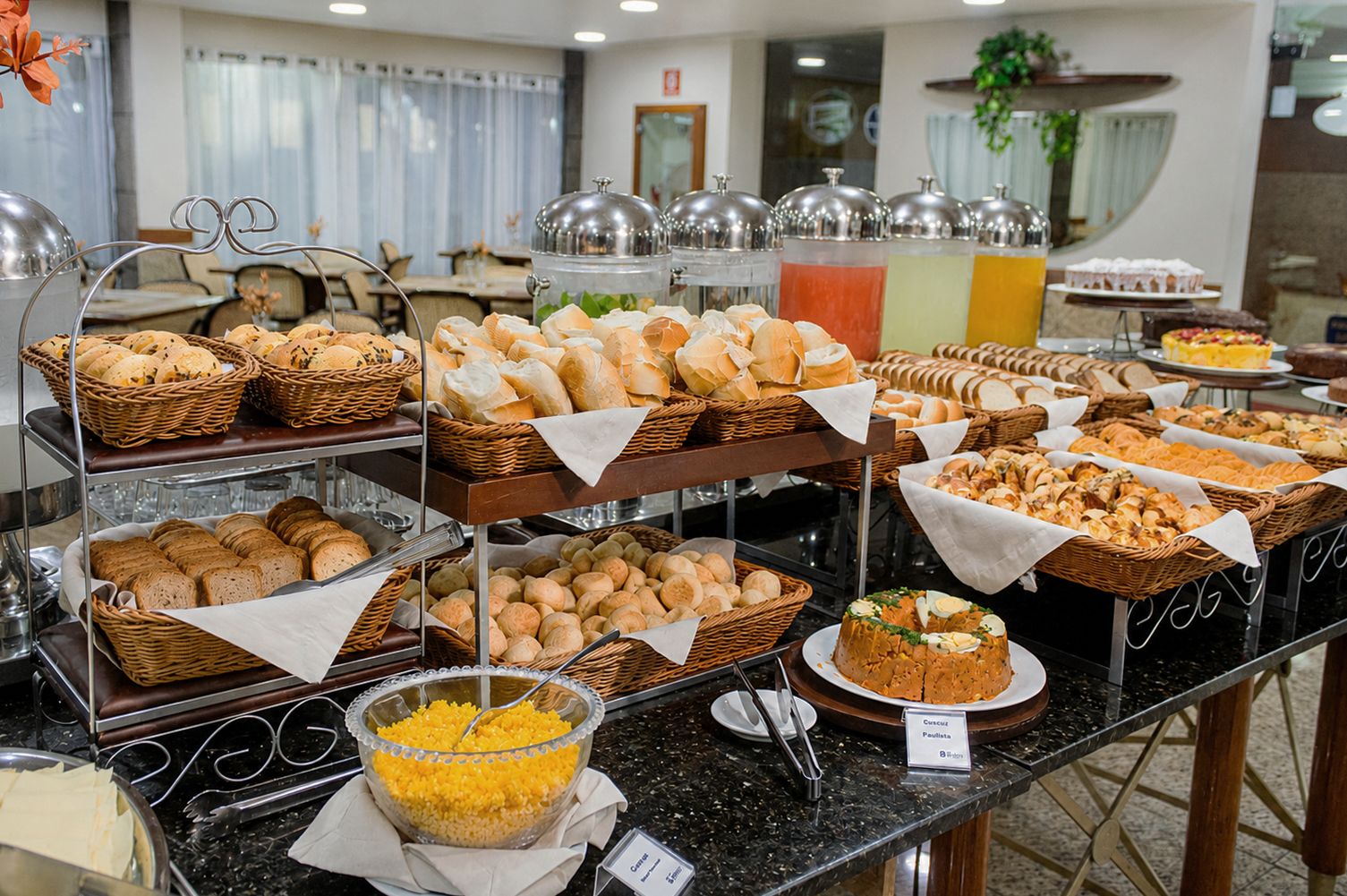 Ein Buffet mit verschiedenen Brotsorten, Gebäck und einer Schale gelber Früchte.