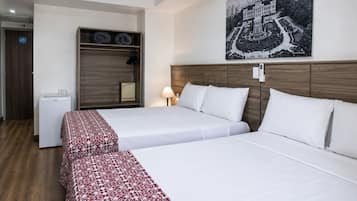 Hotellihuone, jossa on kaksi sänkyä, vaatekaappi, pieni jääkaappi ja seinällä kaupunkimaisemaa esittävä taulu.