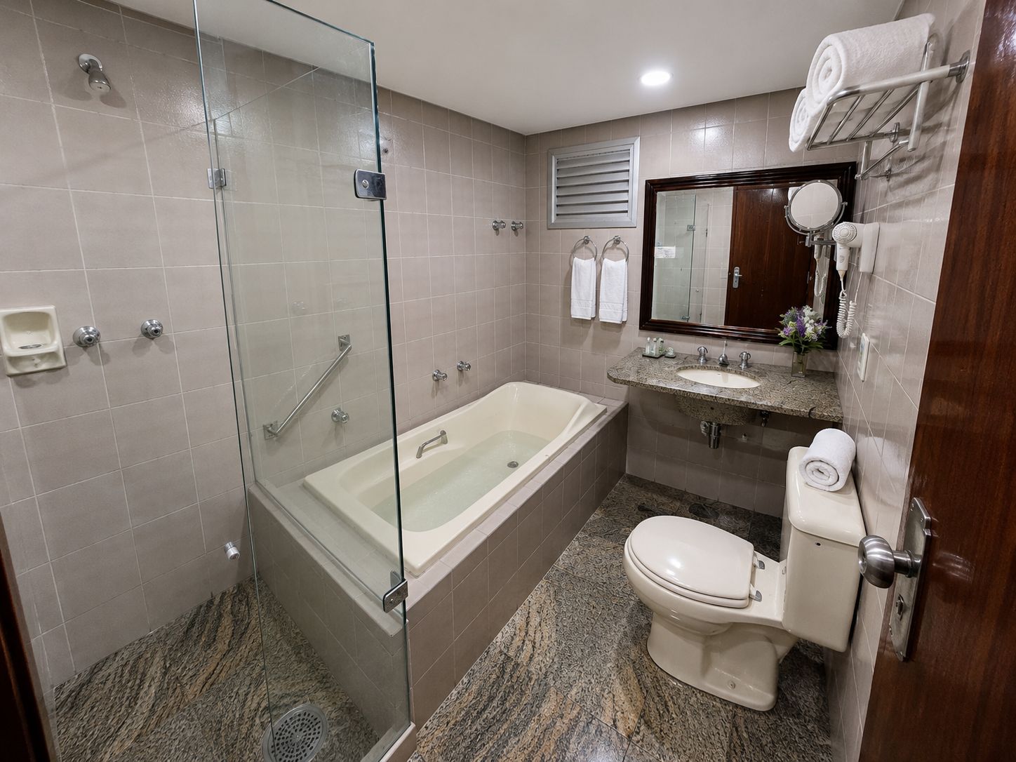 Un baño moderno con ducha envuelta en vidrio, una bañera independiente, un lavabo con tocador y un inodoro.