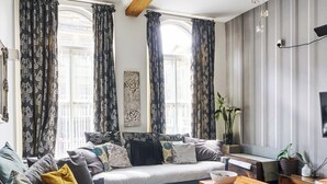 Ein modernes Wohnzimmer mit einer Sofagarnitur, einem Holztisch und einem blauen Teppich mit Muster.
