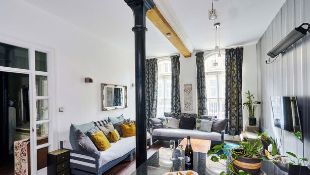 Ein modernes Wohnzimmer mit Sofa, Esstisch und Fernseher.