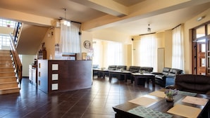 Un vestíbulo de hotel con una recepción, zona de estar y una escalera.