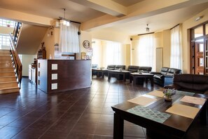 A hotel lobby with a reception desk, seating area, and a staircase.