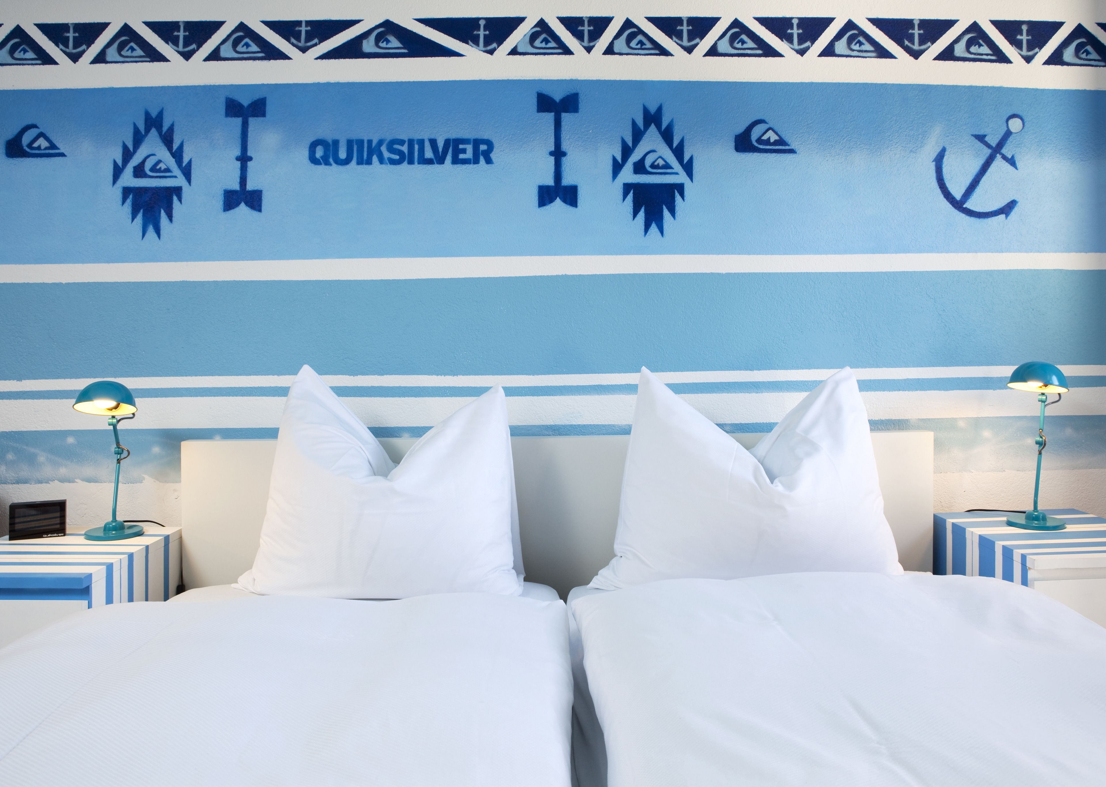 Ein Hotelzimmer mit einem Bett, zwei Nachttischen und einer Wand mit einem maritimen Dekor.