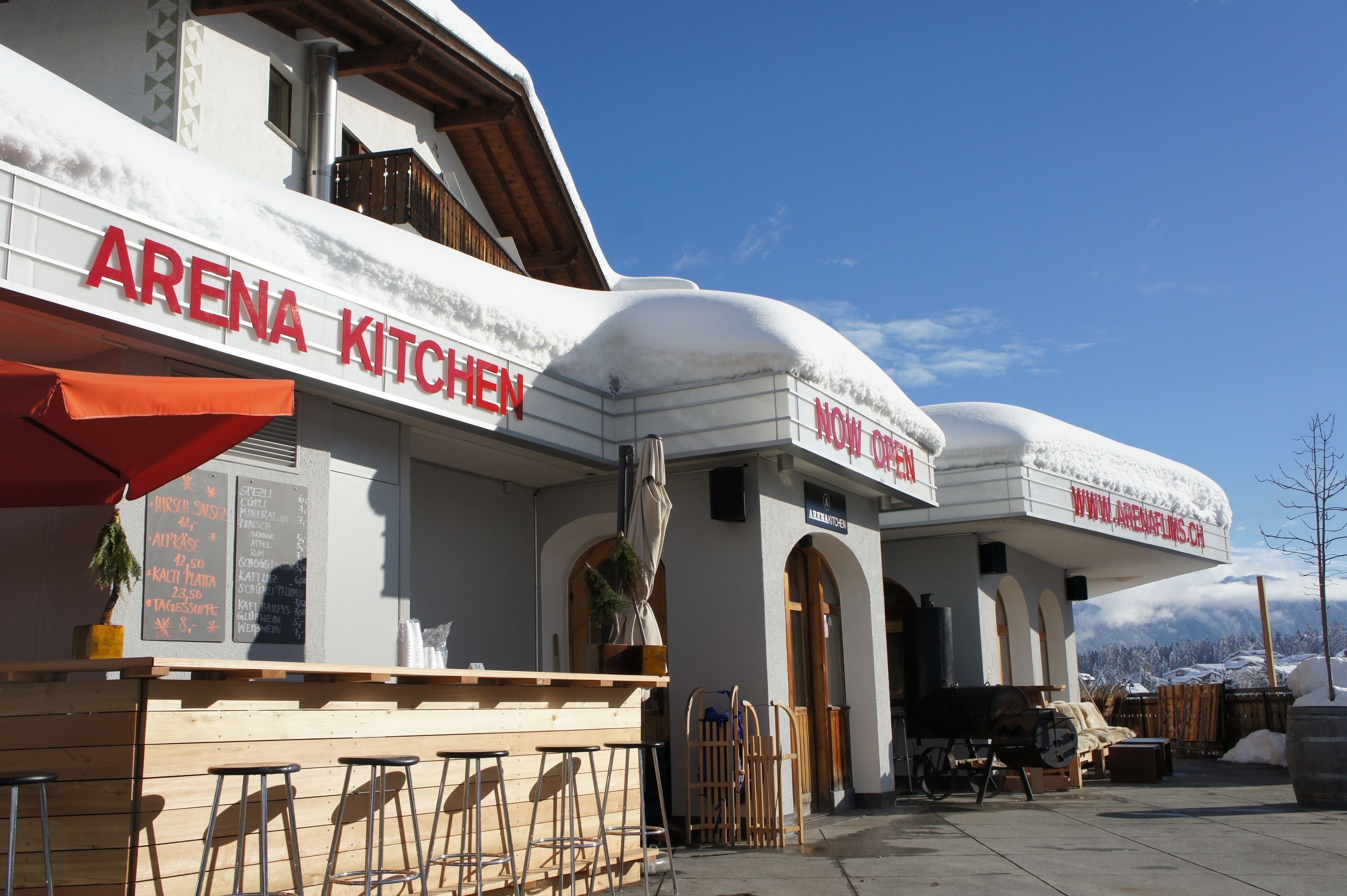 A restaurant named "ARENA KITCHEN" with outdoor seating and snow-covered surroundings.