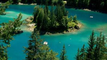 Un lac turquoise, entouré d’une forêt dense, avec une petite île au centre et un bateau amarré près du rivage.
