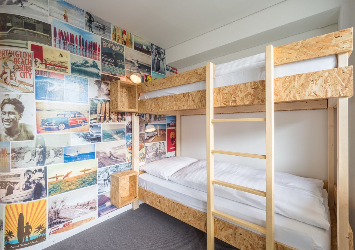 Une chambre avec des lits superposés, un mur étant décoré de divers affiches.