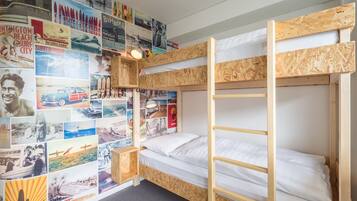 Une chambre avec des lits superposés, un mur étant décoré de divers affiches.